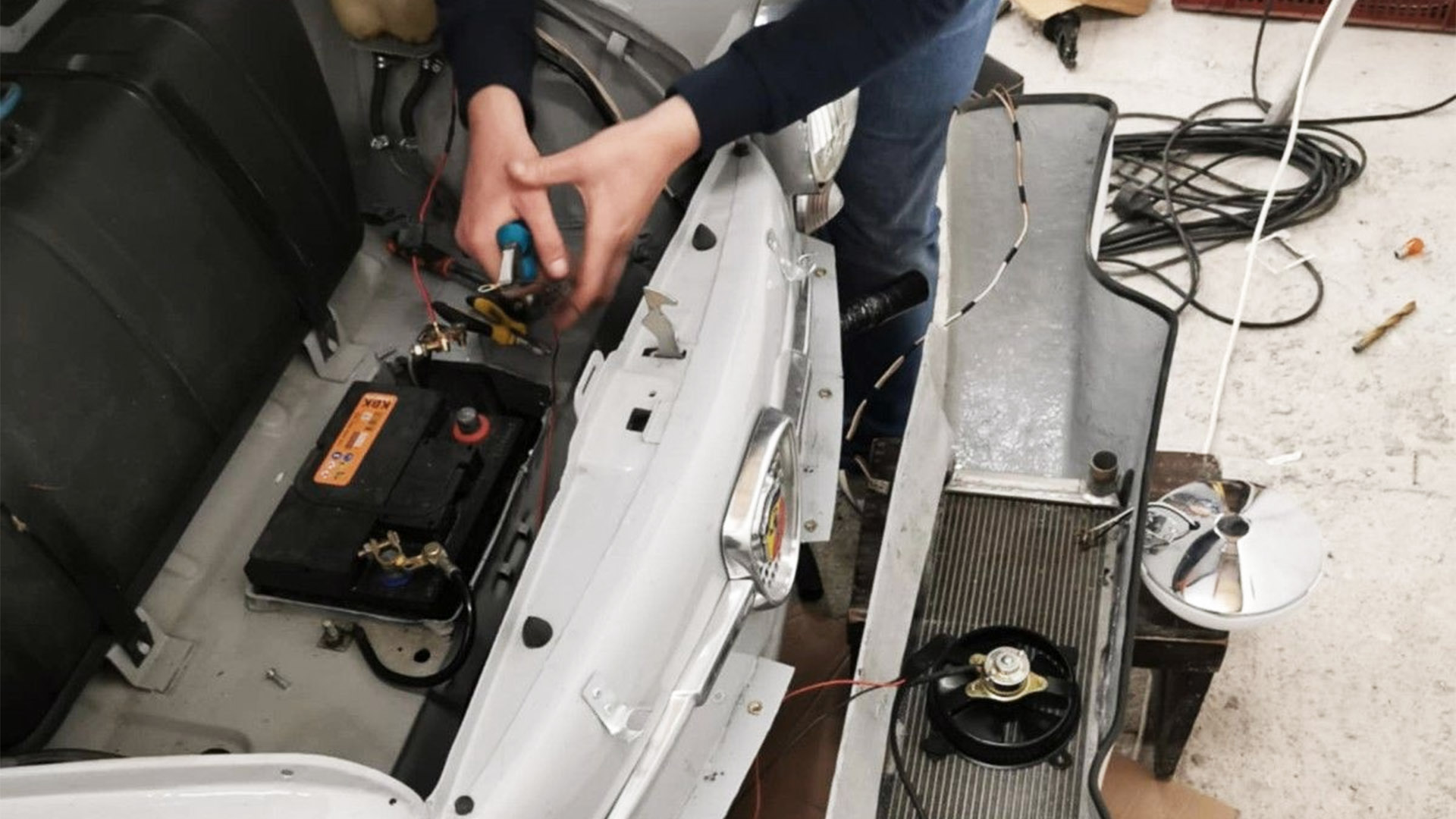 Restauratie van een Abarth 850 Nürburgring met gedemonteerde radiator en montage van onderdelen aan de voorzijde