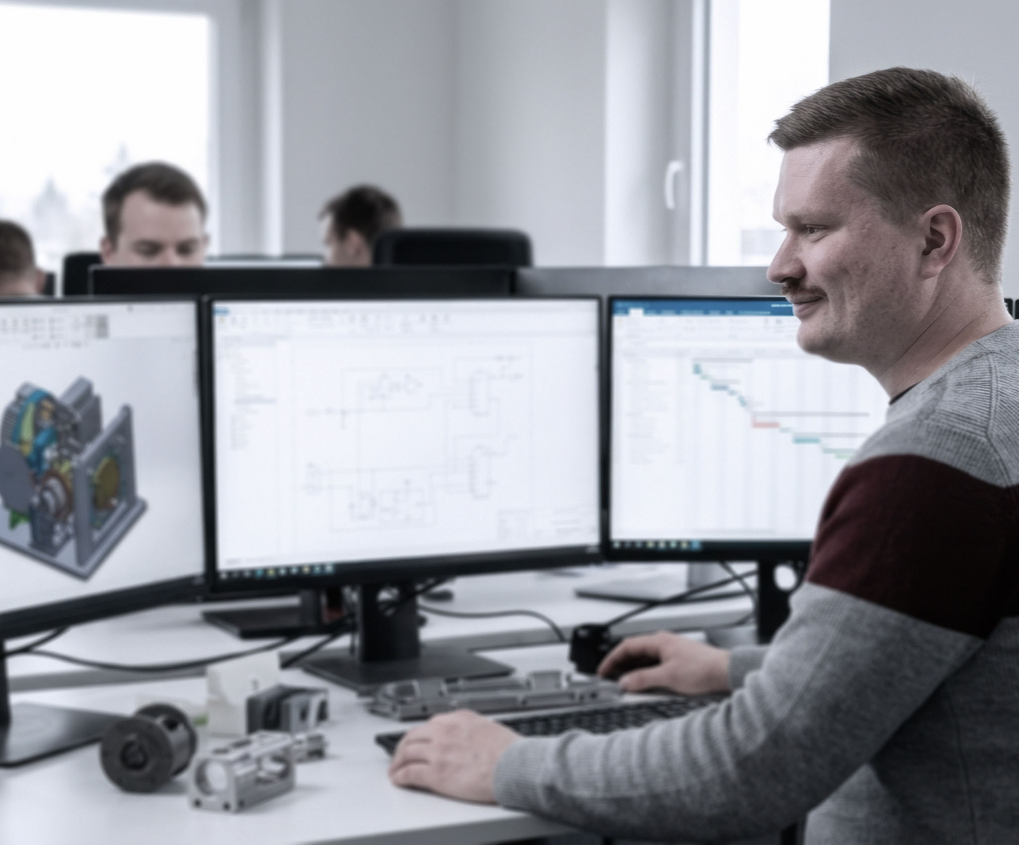 Engineer van ILITAS werkt aan twee schermen met CAD-modellen in teamomgeving