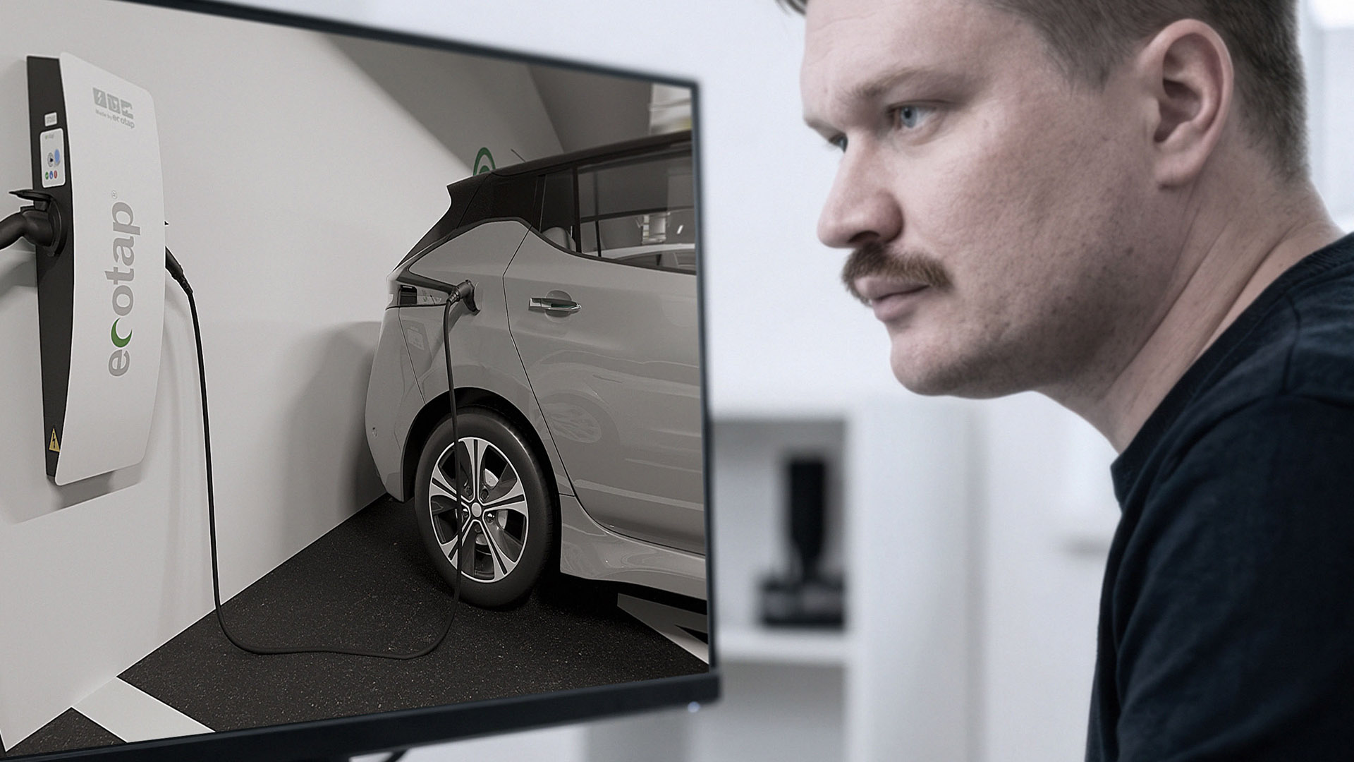 Engineer van ILITAS bekijkt een productvisualisatie van een EV-wandlader op een groot scherm